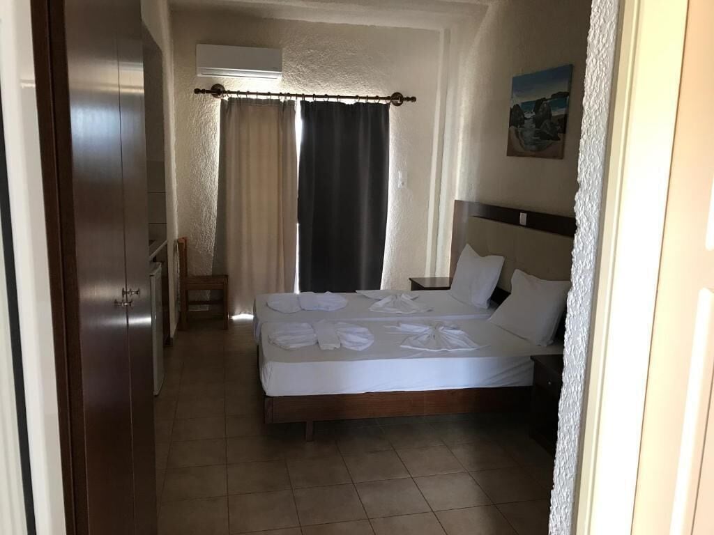 A hotel room with a bed, a nightstand, a chair, and a painting on the wall.