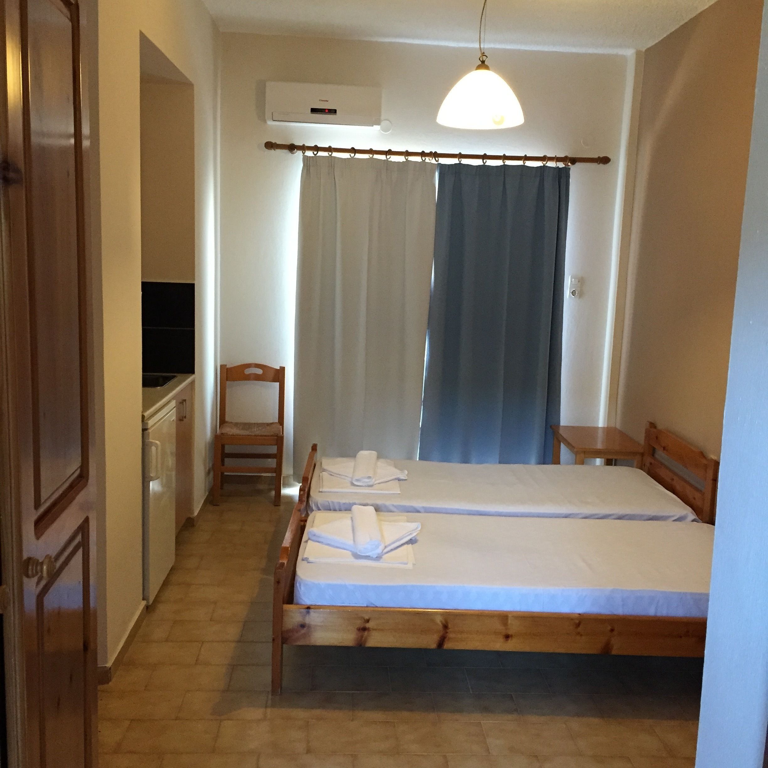 A bedroom with a bed, a chair, a desk, and an air conditioning unit.