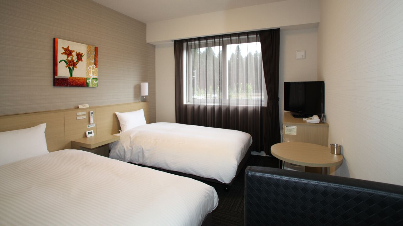 A hotel room with two beds, a television, a small table, and a painting on the wall.