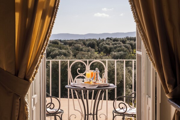 A balcony with a table set for breakfast, overlooking a forested landscape.