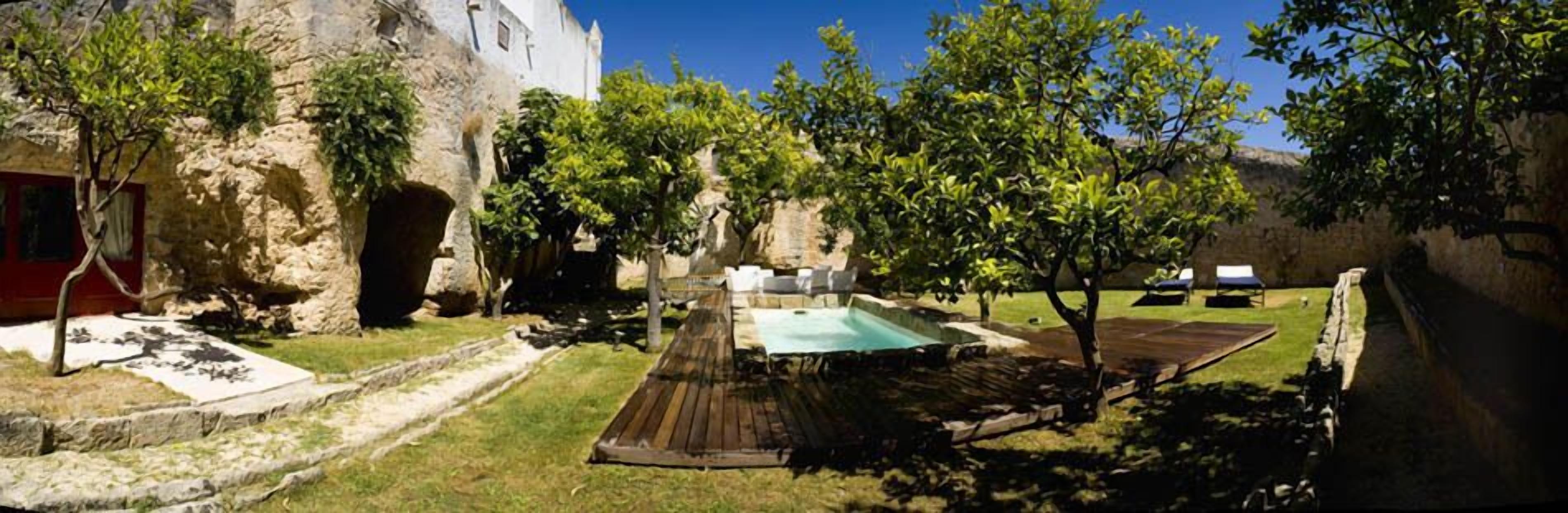 A courtyard with a pool, stone walls, and trees.