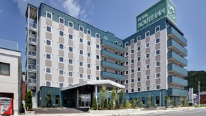 Een modern hotel met een groen en wit gevel, meerdere verdiepingen en een opvallend bord waarop staat 