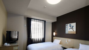 Een hotelkamer met twee bedden, een bureau met telefoon, een televisietoestel en een schilderij aan de muur.