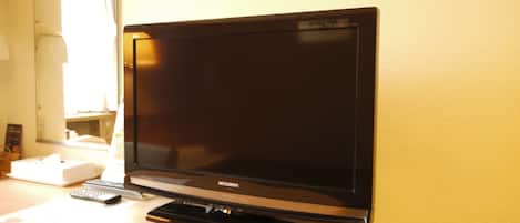 A flat-screen TV mounted on a wooden desk in a hotel room.