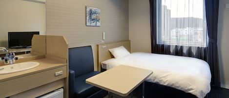 Une chambre d’hôtel équipée d’un lit, d’un bureau, d’une chaise, d’une télévision, d’un lavabo et d’un petit réfrigérateur.