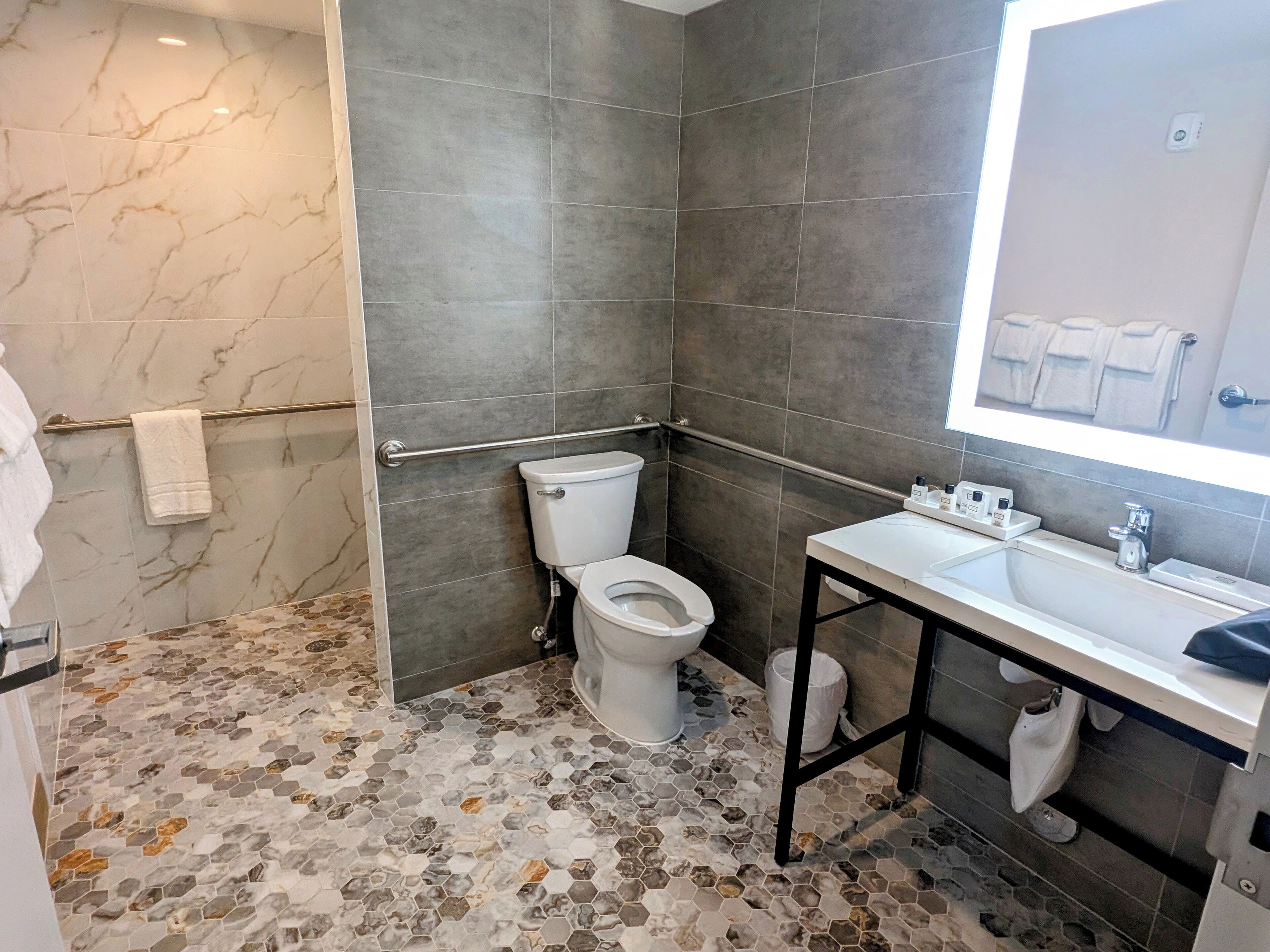 A bathroom with a toilet, a sink, and a mirror.