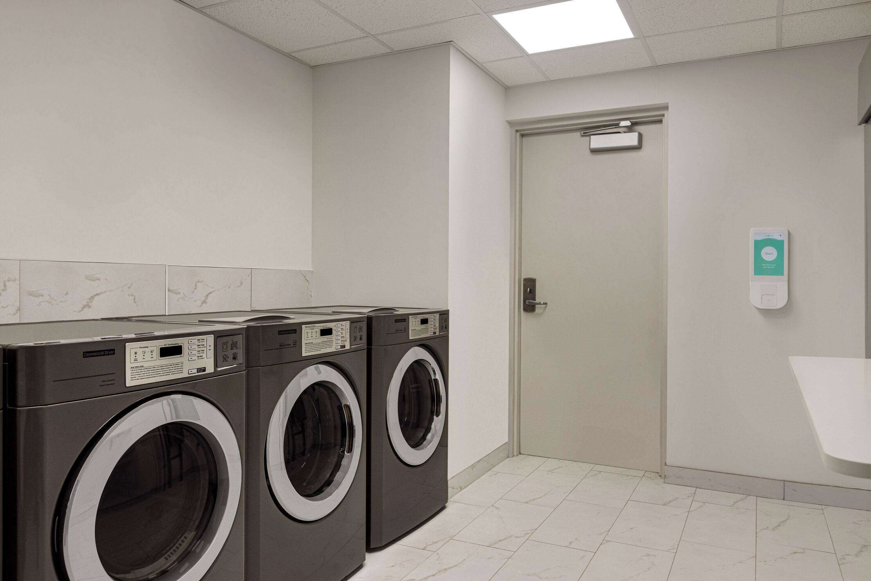 A laundry room with two front-loading washing machines, a white sink, and a door with a sign above it.