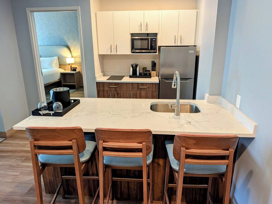 Une cuisine moderne dotée d’un grand îlot central, de chaises en bois et de meubles blancs.