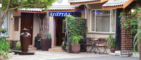 A reception area with a sign, potted plants, and outdoor seating.