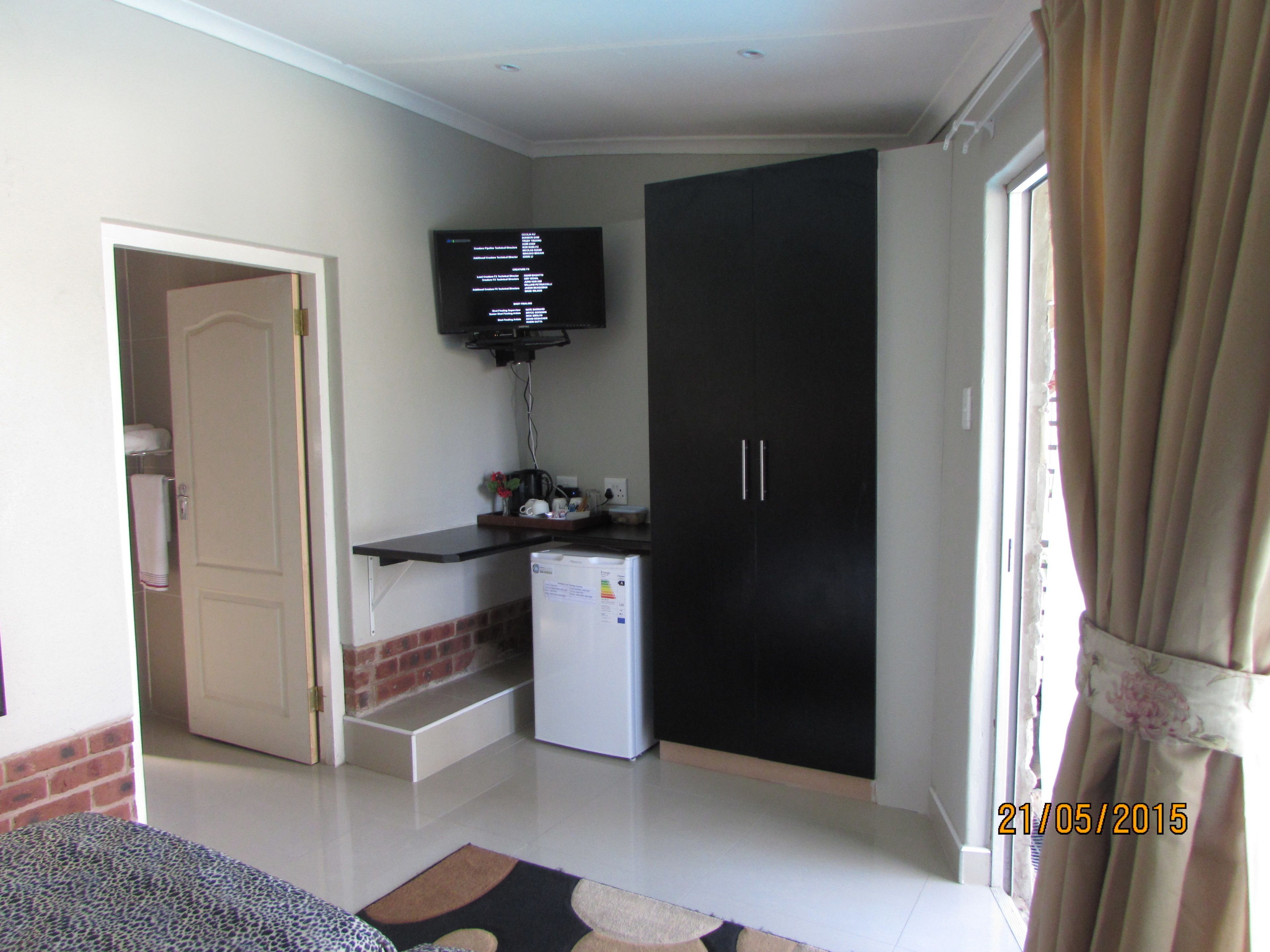 Un espace de vie compact comprenant un coin cuisine, un téléviseur fixé au mur et une armoire.