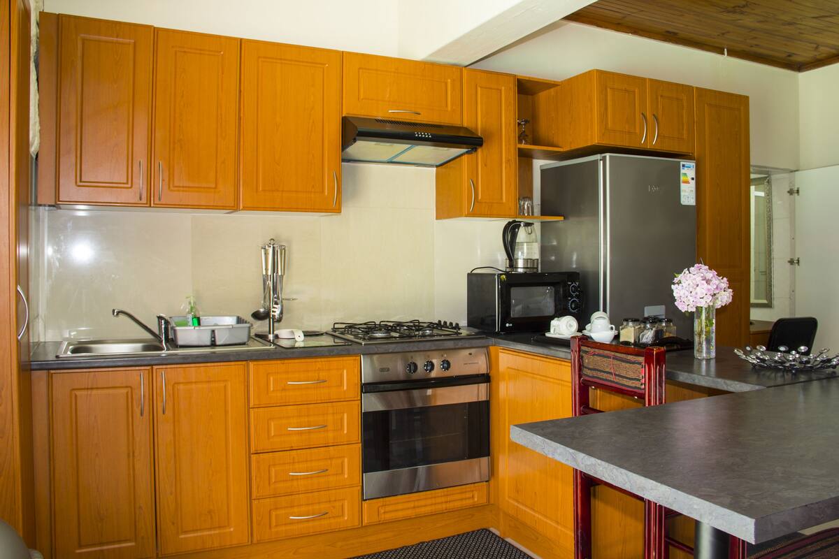 A kitchen with wooden cabinets, a stainless steel refrigerator, a gas stove, and a microwave.