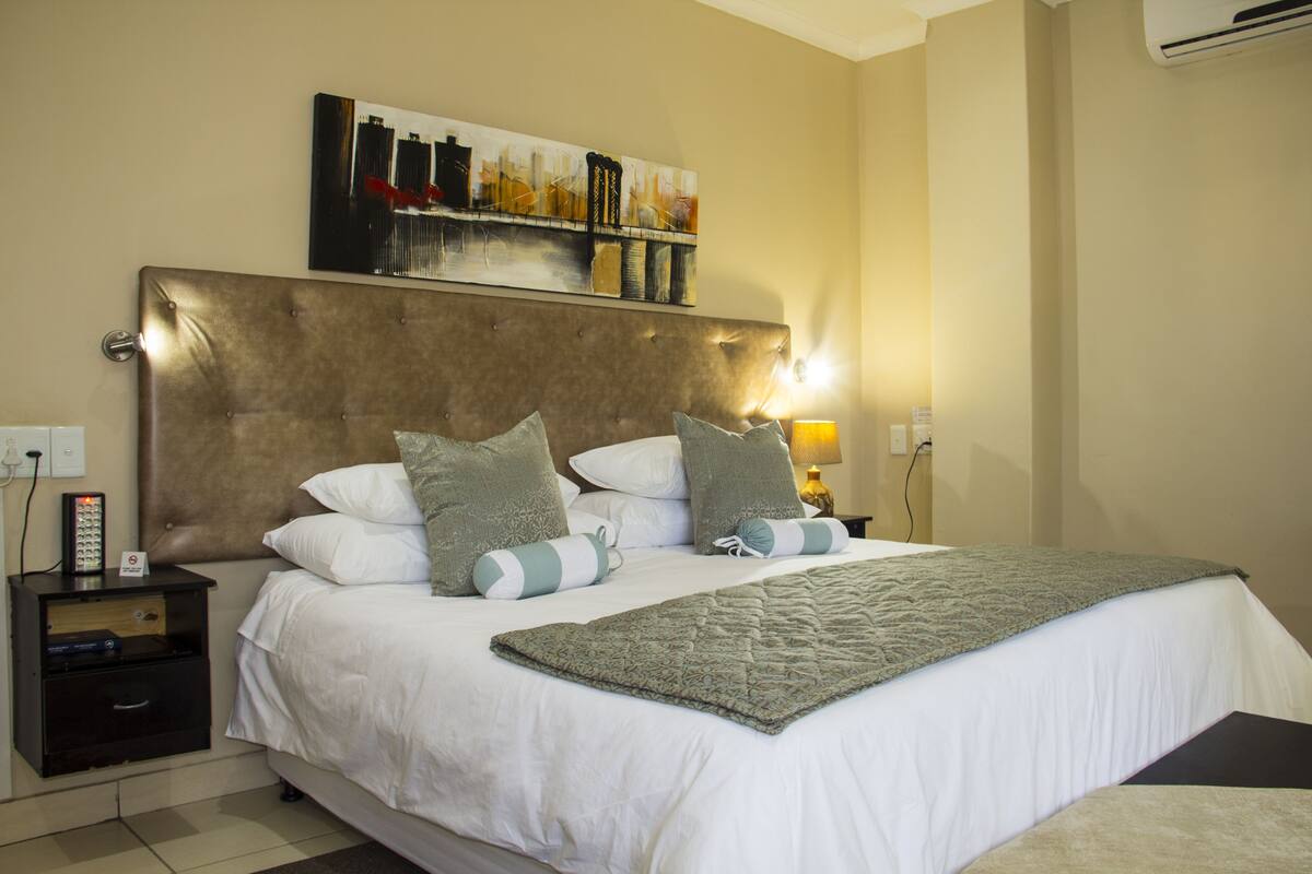 A neatly made bed with a headboard, pillows, and a blanket.