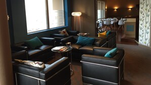 Un salon moderne avec des canapés en cuir noir, une table basse ronde et une grande fenêtre.