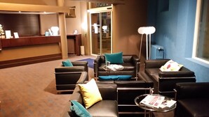 Un hall d’entrée moderne avec des canapés en cuir, un comptoir d’accueil et un grand lampadaire.