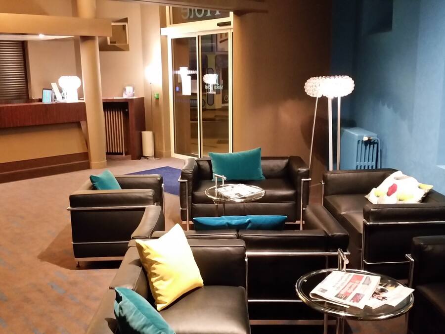 Eine moderne Lobby mit Ledersofas, einem Empfangstresen und einer großen Stehlampe.