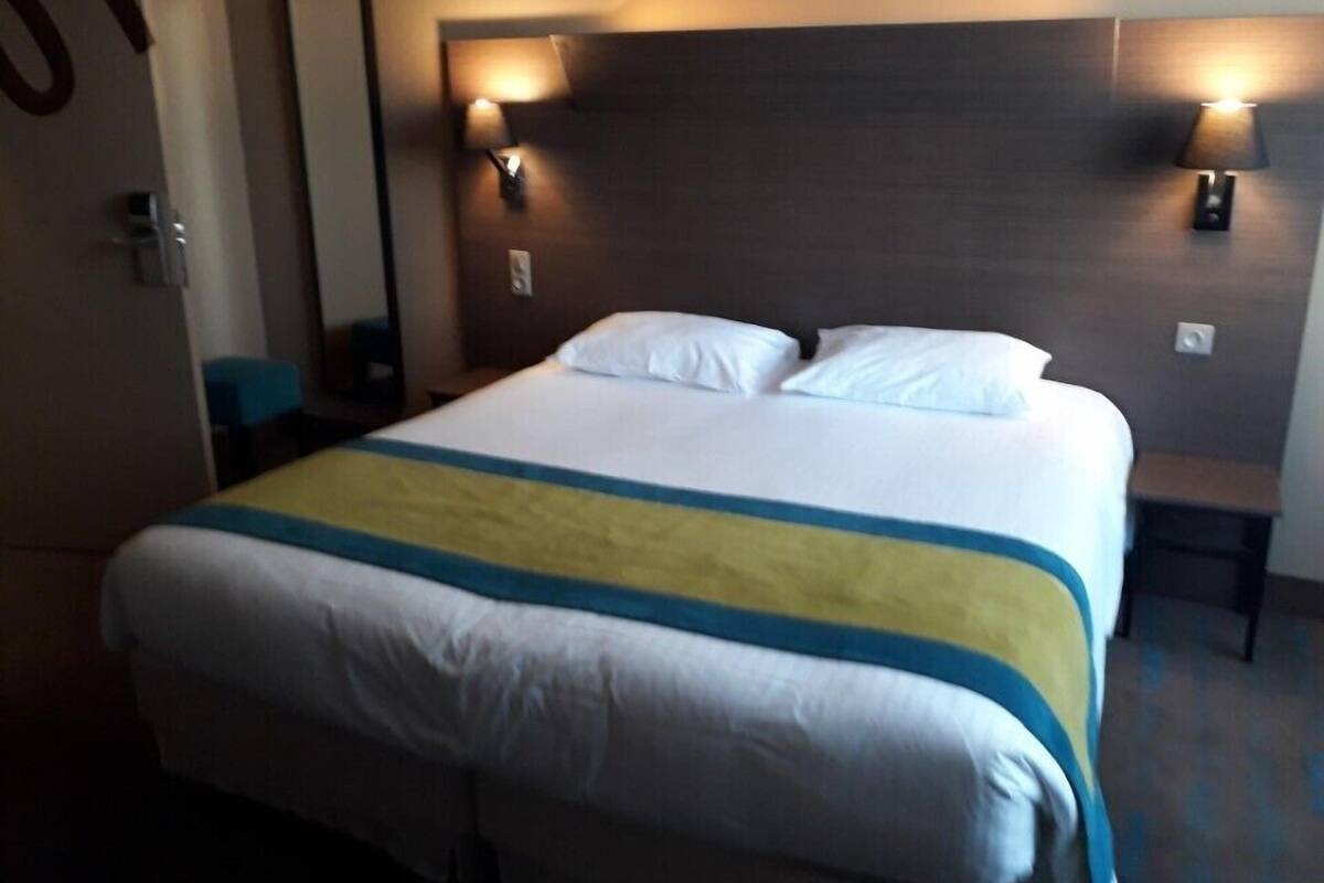 A hotel room with a large bed, two bedside lamps, a mirror, and a small table.