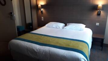 A hotel room with a large bed, two bedside lamps, a mirror, and a small table.