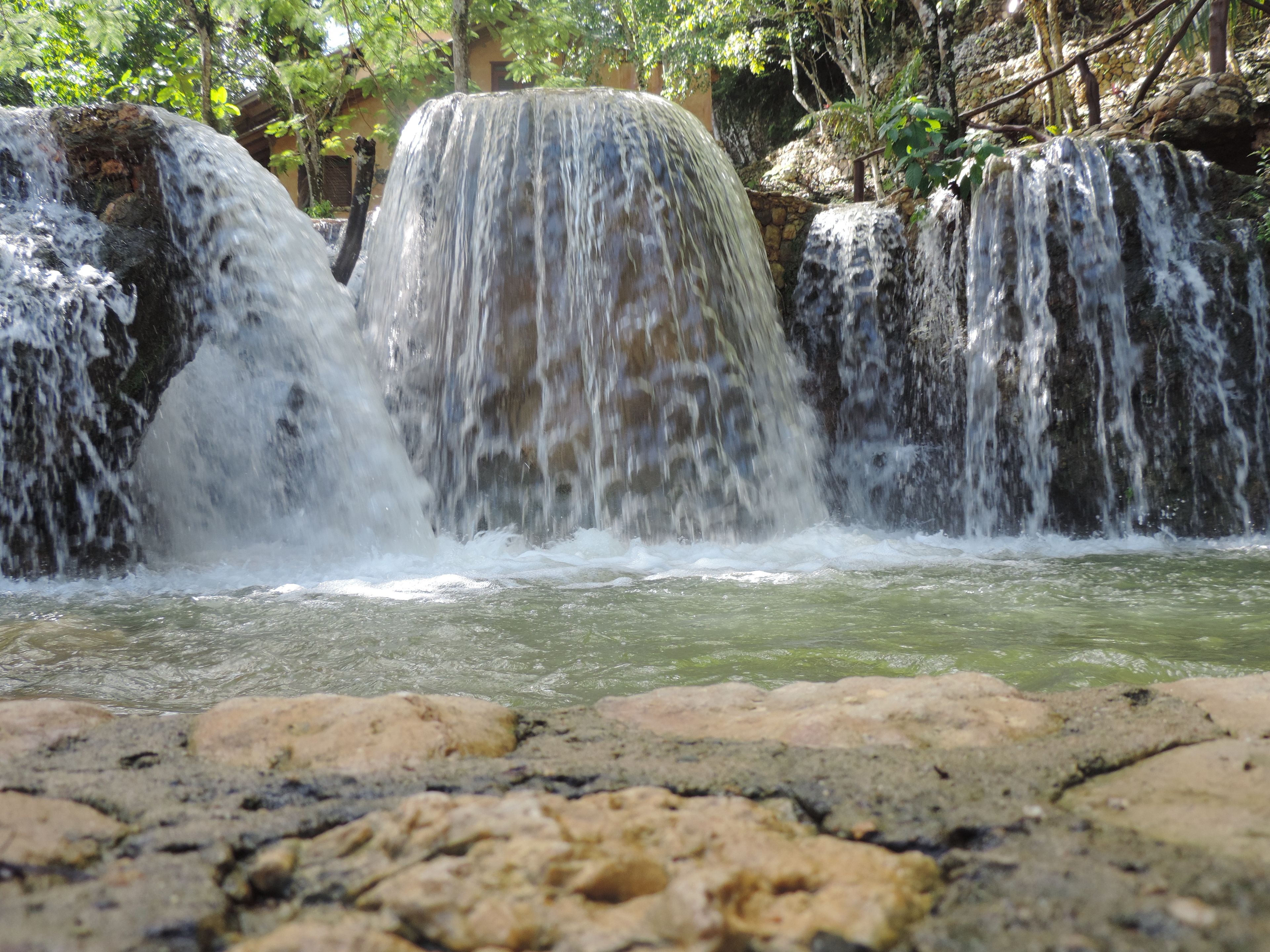 Uma cascata caindo sobre rochas em direção a uma piscina.