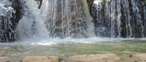 Uma cascata caindo sobre rochas em direção a uma piscina.