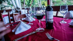 Mesa preparada para comer, con una botella de vino, copas y cubiertos.