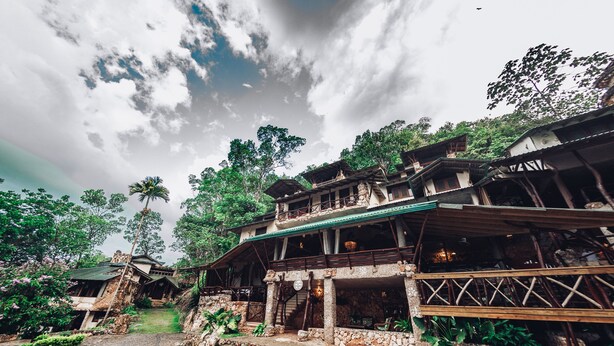 Un edificio rústico de varios niveles, con paredes de piedra y un balcón de madera.