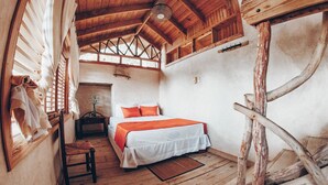 Una habitación rústica de madera con una cama, una silla y una pequeña mesa.