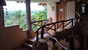 Una escalera rústica con escalones de piedra y baranda de madera, que conduce a una puerta de madera.