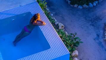 Eine Person sonnt sich auf einer blauen Liege am Pool.