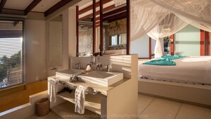 Een moderne badkamer met een dubbele wastafel, een grote spiegel en een hemelbed.
