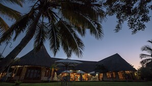 Een resort met rieten daken, terrasjes en palmbomen.