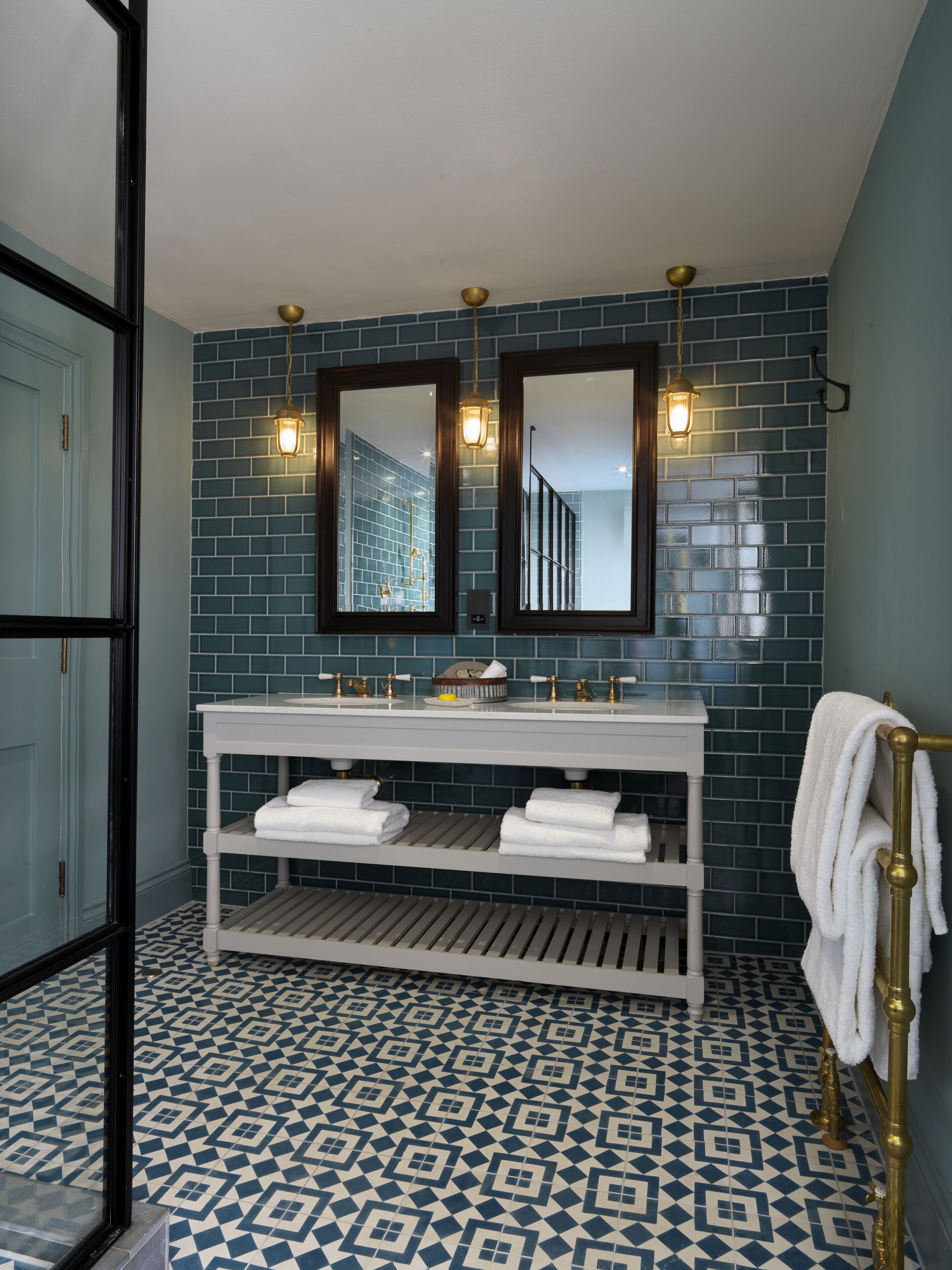 A bathroom with a white vanity, two mirrors, and a tiled floor.