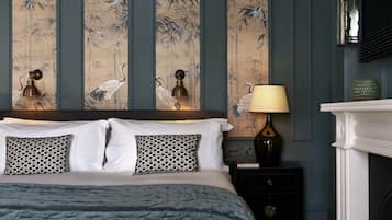 A bedroom with a large bed, two wall-mounted lamps, a fireplace, and a wall with a bamboo print.
