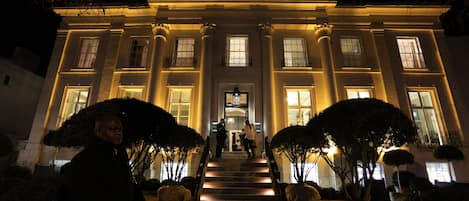 A grand building with a symmetrical facade, large windows, and a central entrance with steps leading up to it.