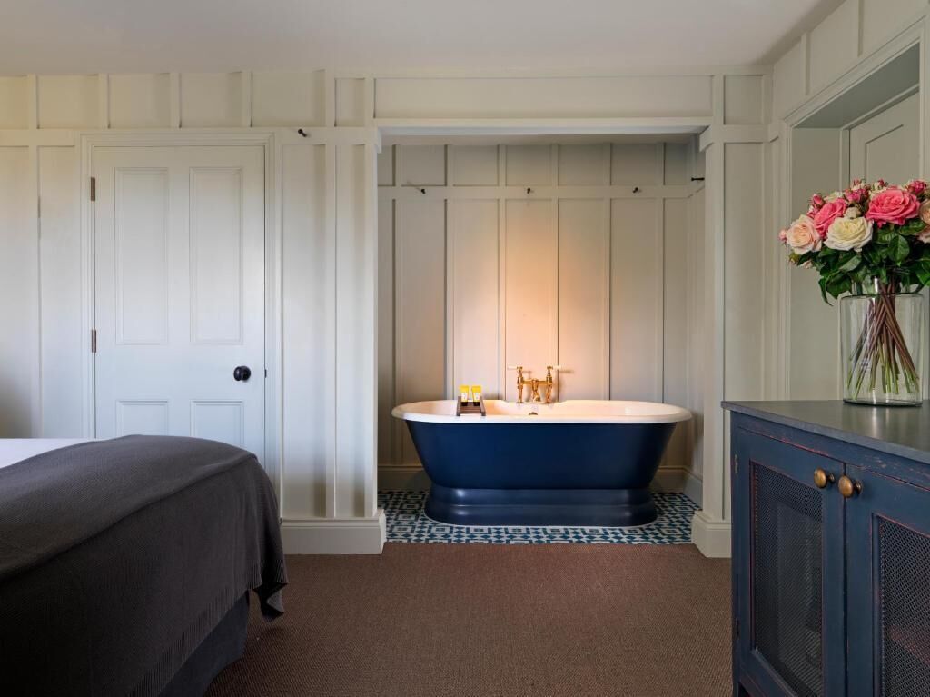Een badkamer met een vrijstaand bad, een bed en een kast met een bloevas.