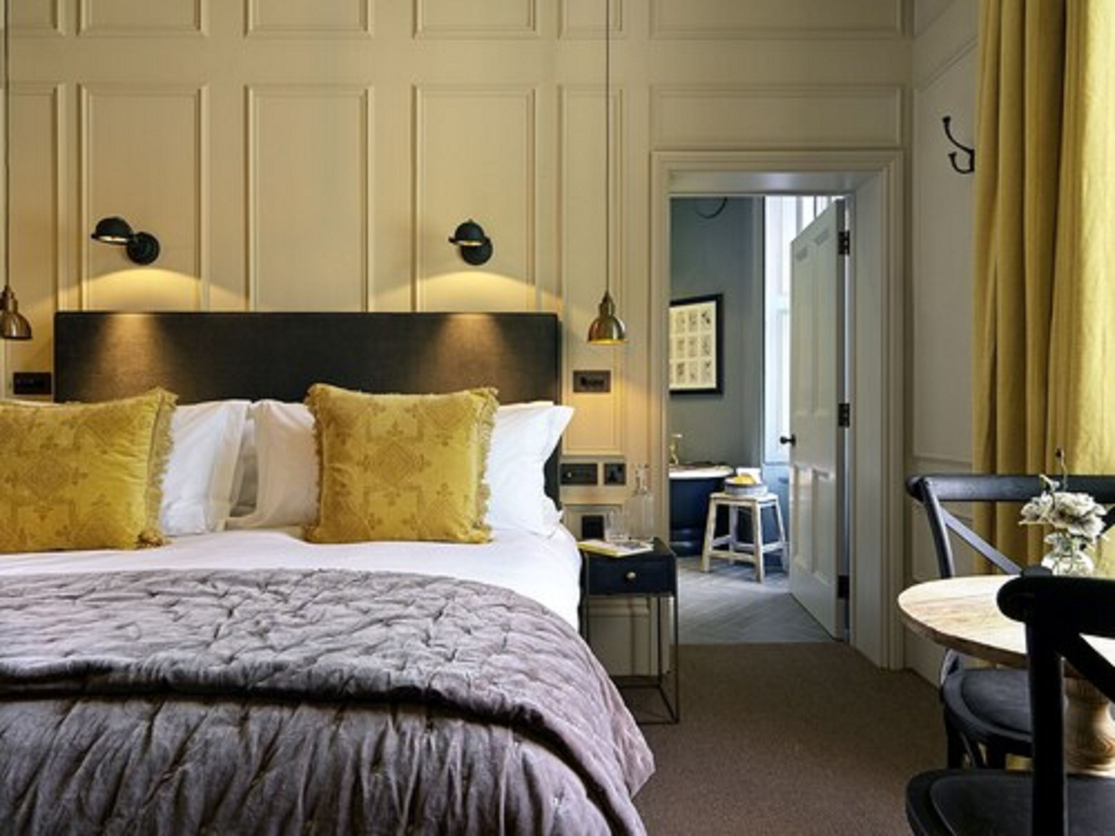 A hotel room with a large bed, bedside lamps, a desk, and a chair.