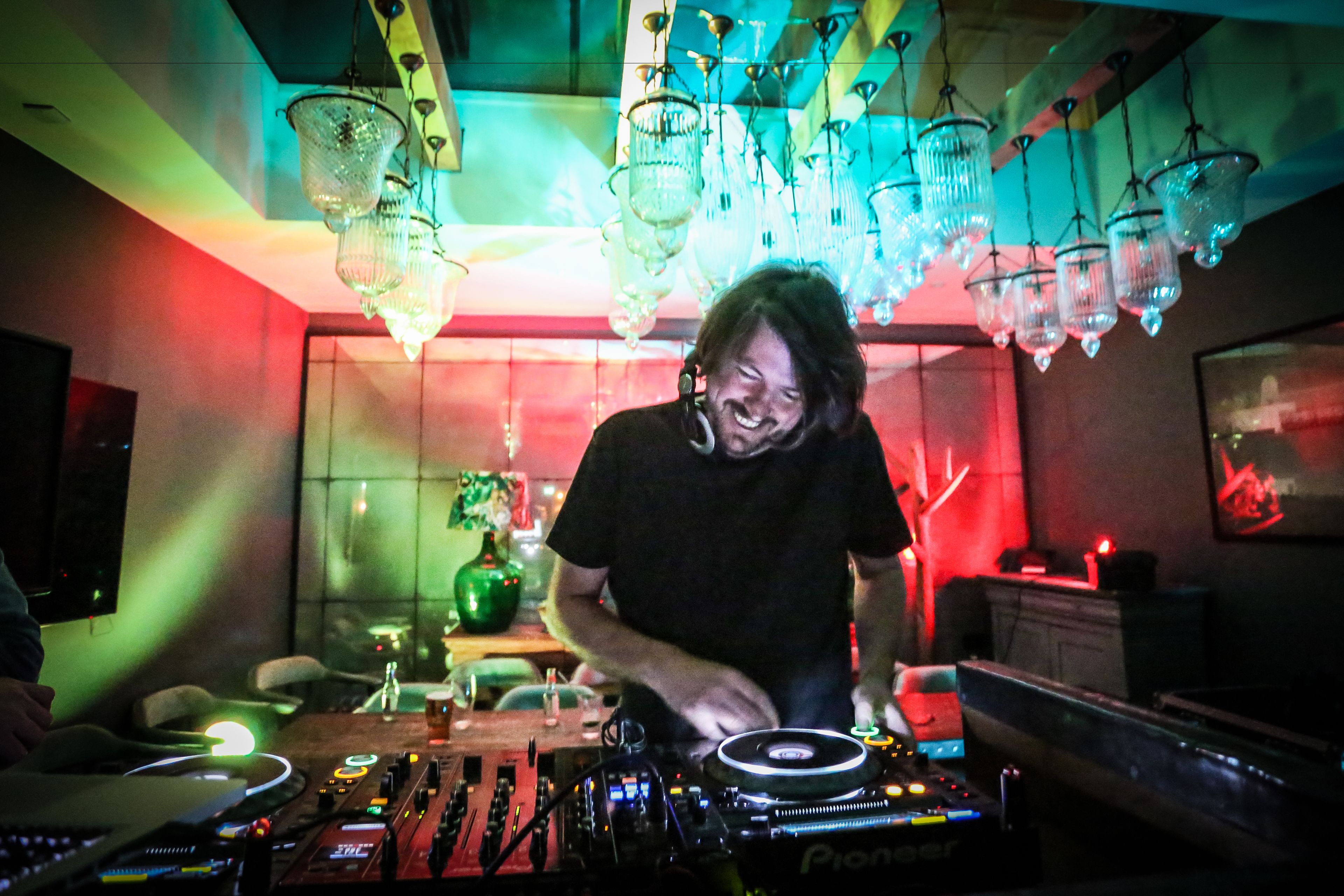 A DJ booth with a Pioneer mixer, surrounded by various DJ equipment.