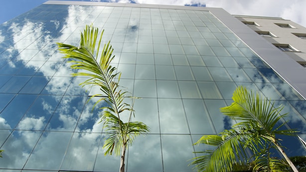 Un edificio moderno con fachada de vidrio que refleja el cielo y las nubes.