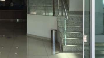 A modern interior with a staircase, a trash bin, and a glass door.
