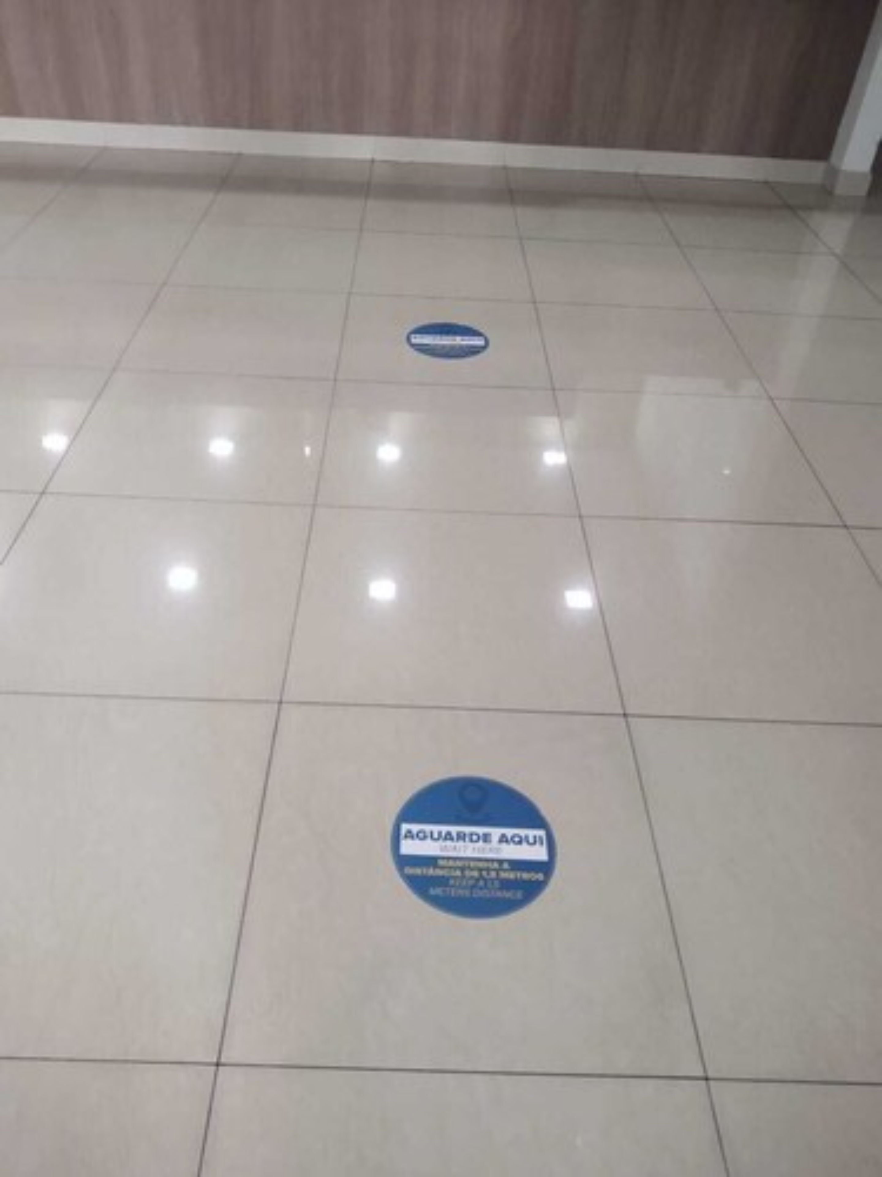 A clean, tiled floor with a blue circular sign indicating social distancing measures.