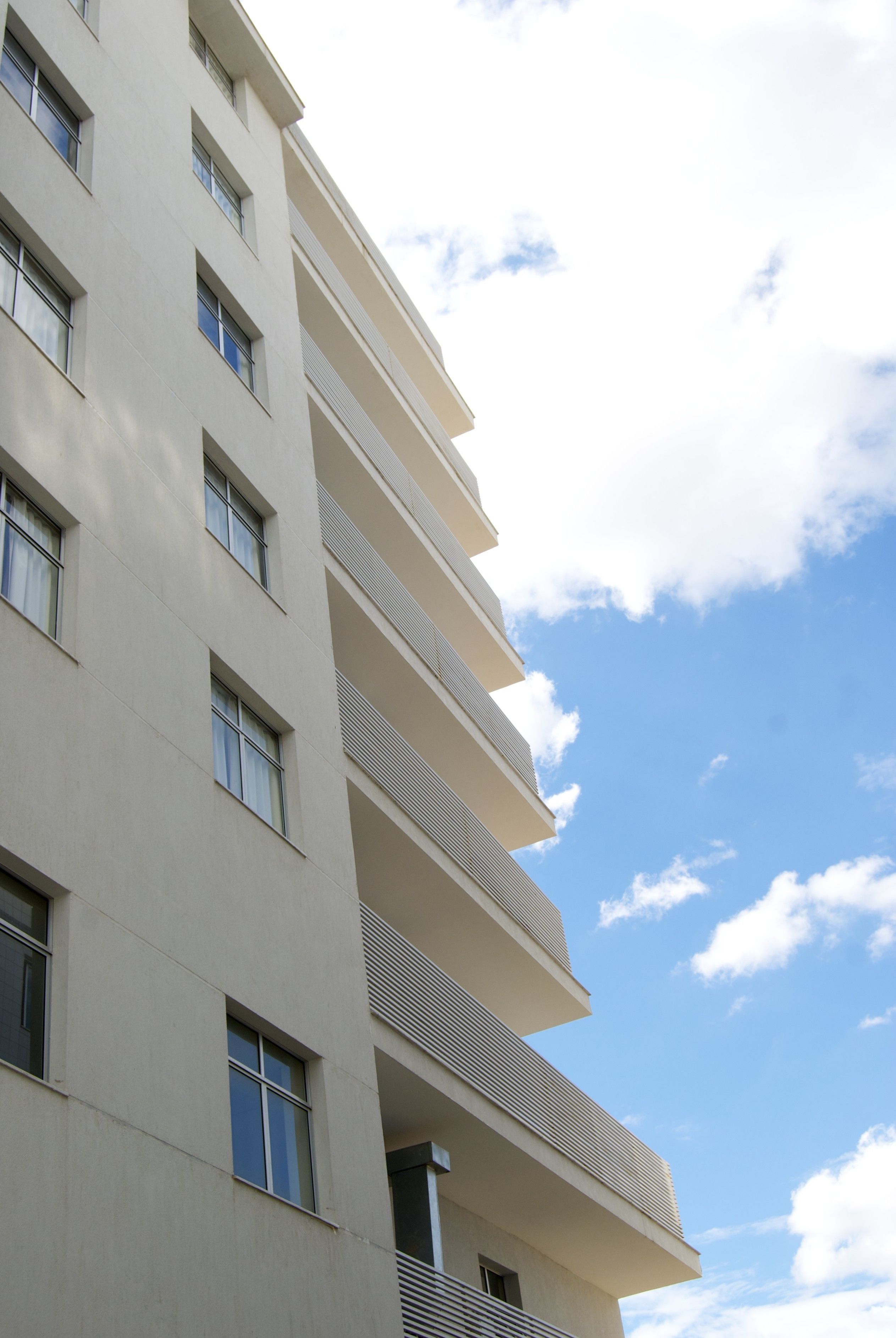 Un immeuble à plusieurs étages doté d’une architecture moderne, avec des balcons et de grandes fenêtres.