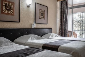 A hotel room with a large bed, two bedside tables, and a view of a balcony with metal railings. - Hotel María de la Luz (Valladolid)