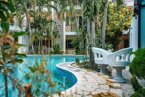 A swimming pool with a stone pathway, surrounded by tropical plants and a white balustrade. - Hotel María de la Luz (Valladolid)