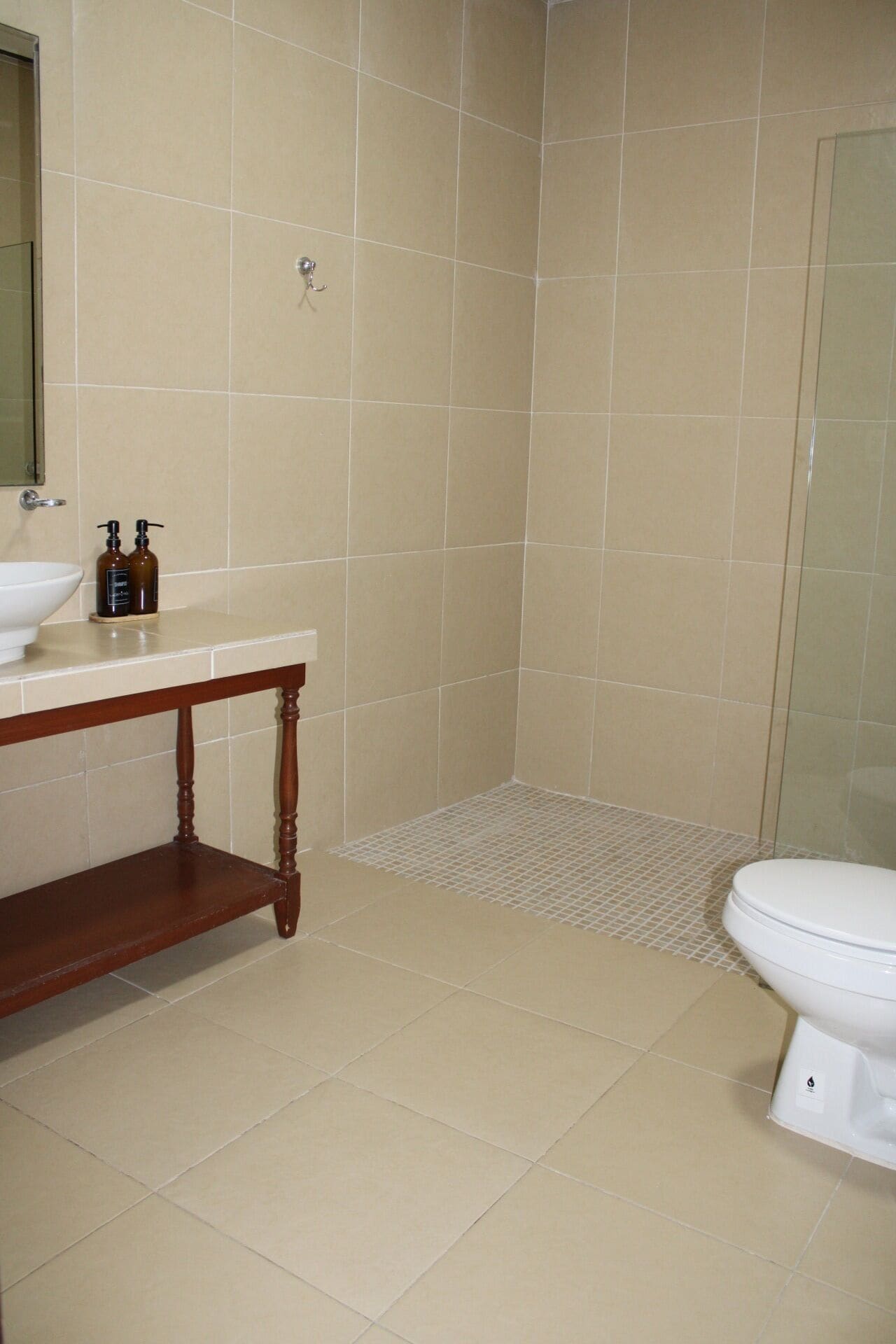 Un baño con lavamanos, espejo, artículos de aseo, ducha y retrete.