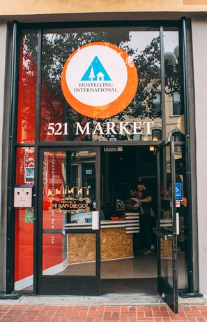 De gevel van Hostelling International 521 Market, met een goed zicht op de ingang en een persoon binnen.