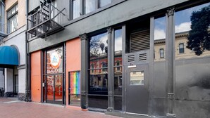 Un immeuble doté de grandes fenêtres, d’une échelle de secours et d’une devanture de magasin avec une enseigne colorée.