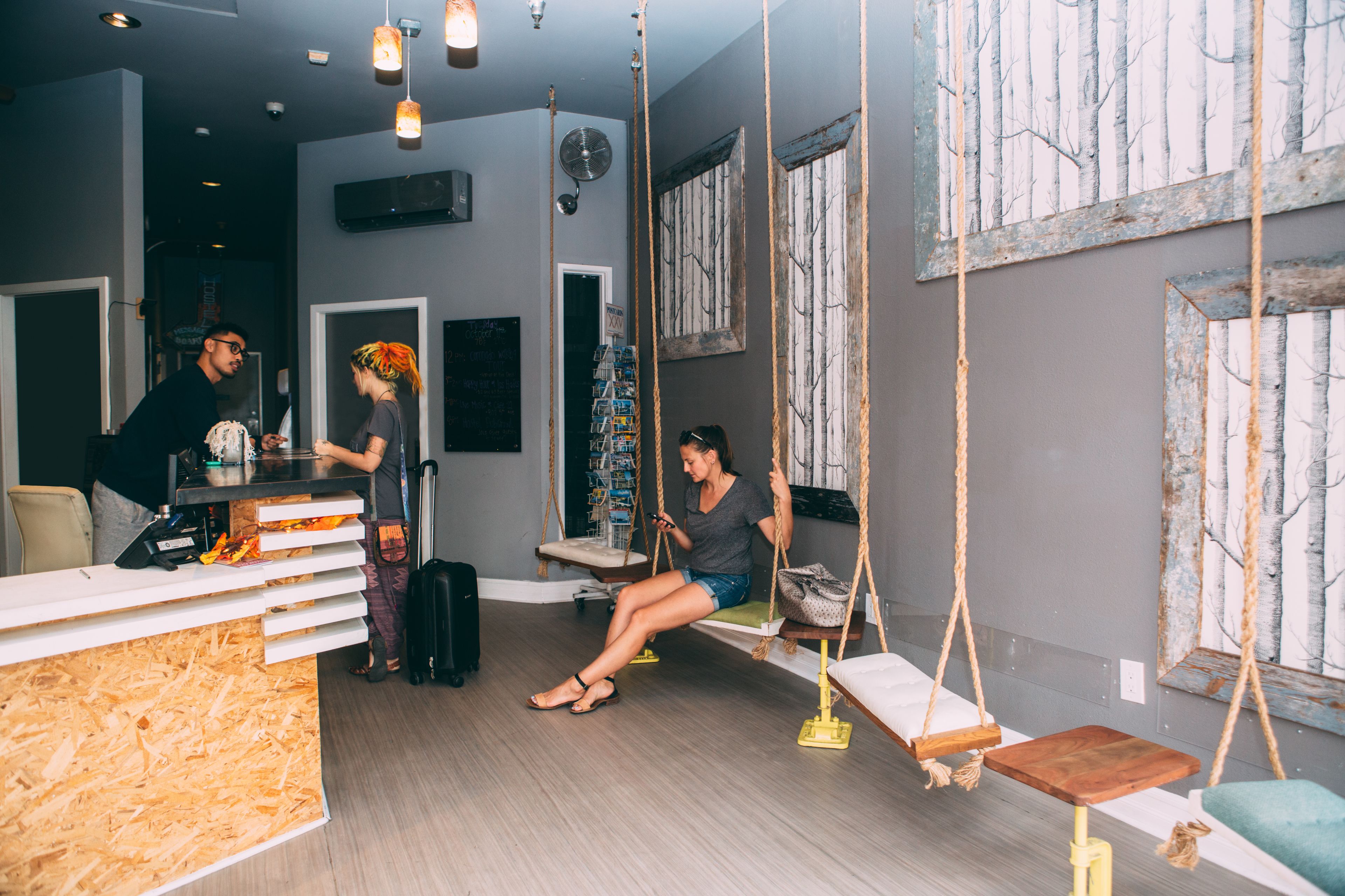 A reception area with a wooden counter, a seating area with swings, and a large window with a view of trees.