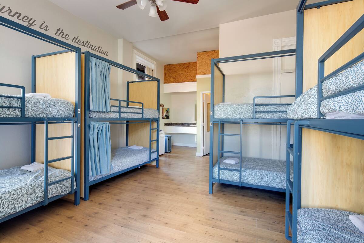 Habitación tipo dormitorio con literas, piso de madera y ventilador de techo.