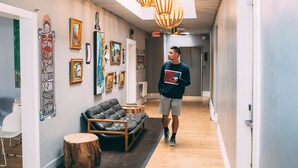 Un couloir avec un canapé, des œuvres d’art et un luminaire au plafond.