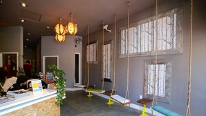 Un espace d’accueil avec un bureau en bois, une plante verte et une rangée de balançoires.
