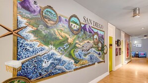 Un couloir orné d’une grande fresque représentant un paysage côtier, avec les inscriptions « SAN DIEGO » et « LA JOLLA ».
